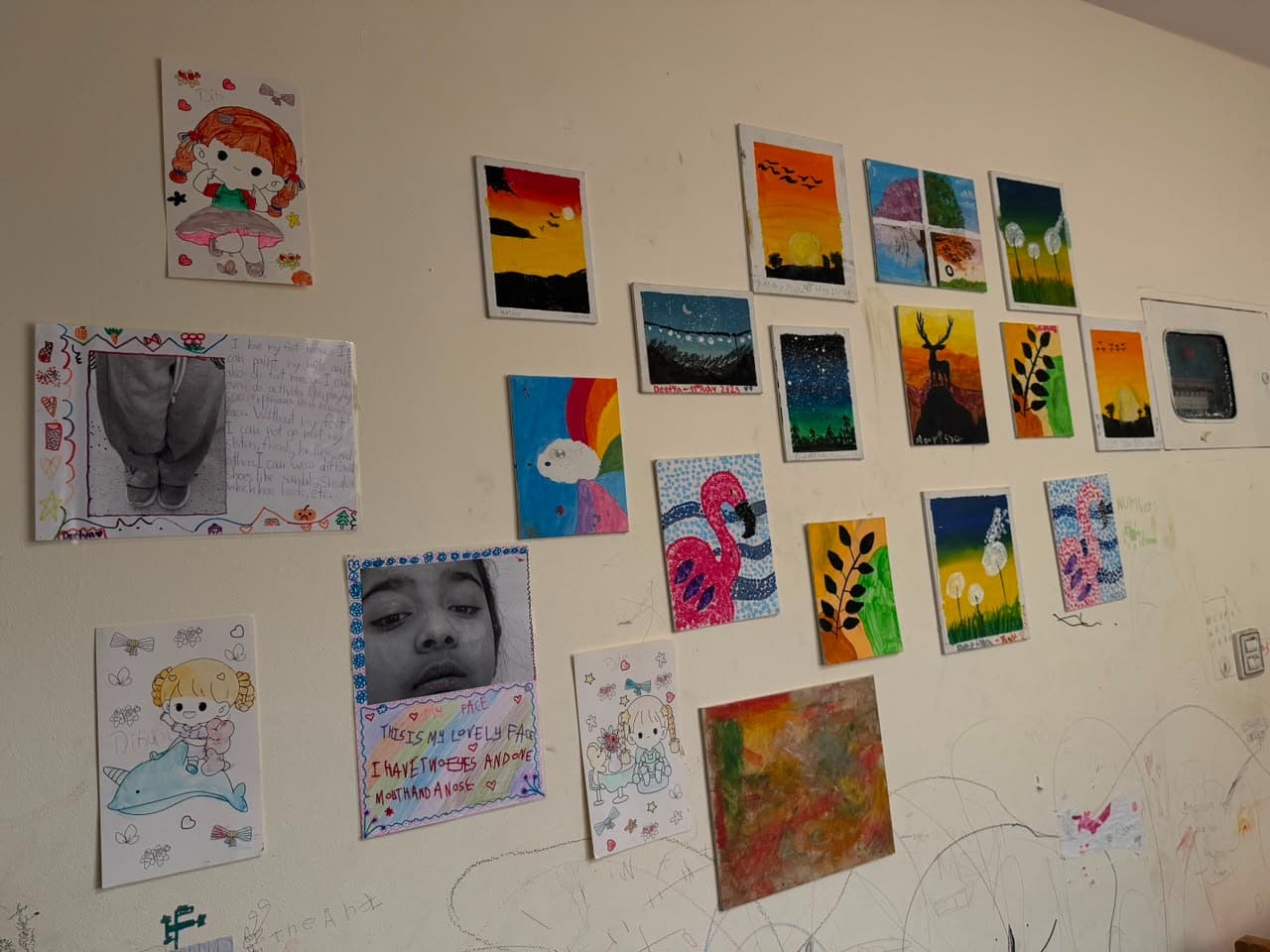 A wall covered with children's paintings and drawings pinned up in a home creative space.